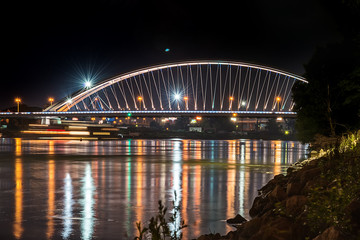 Obraz premium Bratislava, Slovakia May 23, 2018: Apollo bridge over river Danube in Bratislava with reflection on water.