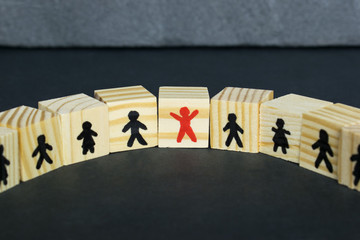 Wooden cubes with drawn people figures on the dark background, teamwork concept.