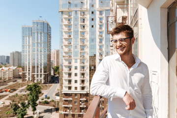 Smiling young man standing on a balcony