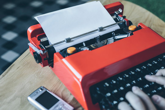 Cell phone and hands using red typewriter