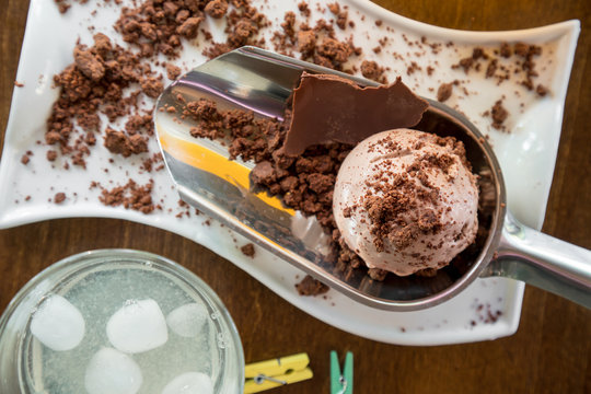 White plate of chocolate ice cream scoops sprinkled with chocolate on wooden table