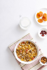Muesli served with milk, honey, almonds, dried apricots and dried cranberries. Vertical shot. Flatlay.