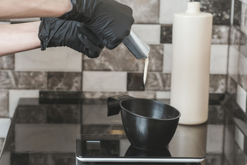 Hair stylist hands preparing a dye in a container