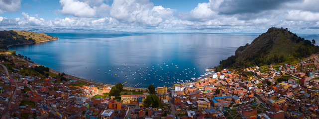 Aerial panorama of the lake of Titicaca and the town of Copacobana during the sunny calm day, Bolivia - obrazy, fototapety, plakaty