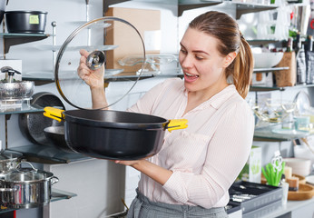Smiling woman is choosing new stewpot for her house in  shop