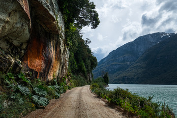 Gravel Patagonian road between lake and mountain. Road located in place named Valle Exploradores  in Chile