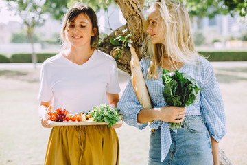 Young happy women with healthy food for summer picnic outdoor