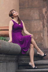 Fototapeta na wymiar eautiful woman in purple dress sitting on the steps. People