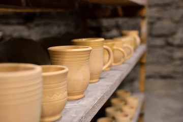 Pottery (pots, mugs, cups, vases) on the shelves in the workshop. Pottery.