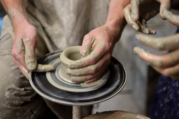 Potter teaches the student pottery in the workshop. Pottery, family craft. Collaboration.