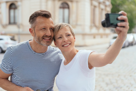 Middle-aged couple posing for a selfie in town