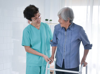 Nurse helping Elderly Woman Using Walking Frame.