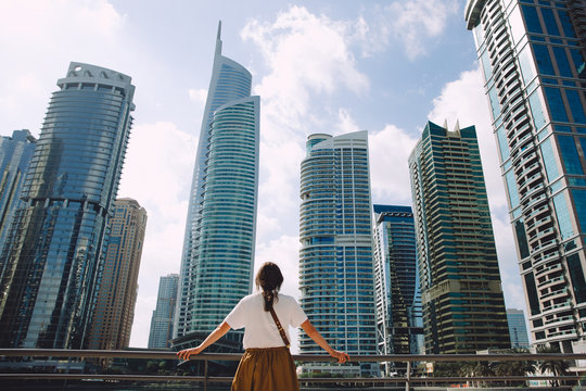 Female traveler looking at modern city architecture against blue sky, Dubai, UAE