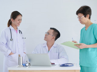 Doctors and seniour nurse looking at laptop together.