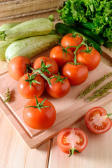 Close-up of fresh, ripe tomatoes with vegetables on wooden background. Top view.
