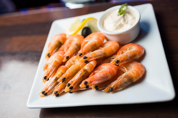 Appetizer of a boiled shrimp on a white plate with a white sauce