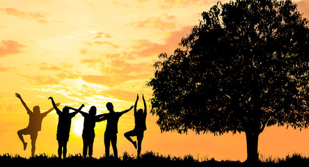 Silhouetted photo.They are standing with big tree and show hand together.They are enjoying and also they are watching the evening glow together. They are happy in good time.  Photo concept for Silhoue