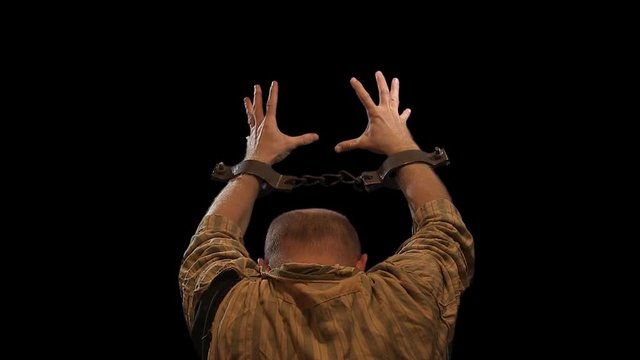 Prisoner with chained hands pray to the Lord. Alpha channel. Shot with Canon MXF HD422.