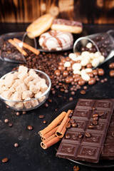 Brown sugar in a glass bowl next to candies and sweets on dark vintage wooden background