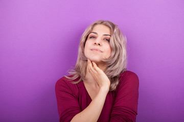 Happy smiling young blonde woman portrait on purple background