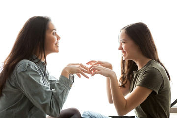 Two sisters playing with each other and having a great time together over white background