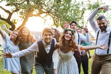 Bride, groom, guests posing for the photo at wedding reception outside in the backyard. - obrazy, fototapety, plakaty