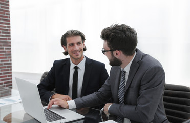 Two business men working on a laptop