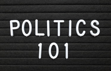 The words Politics 101 in white plastic letters on a black letter board as an introduction to the basics for learning the subject
