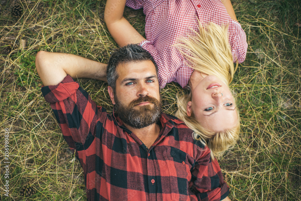 Wall mural couple in love relax on green grass. bearded man and woman with long blond hair. hipster and girl en