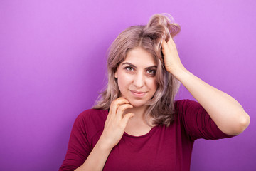 Portrait of young attractive blonde woman in studio photo on purple background