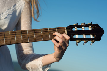 Closeup of female playing guitar on beach in summer sunny day