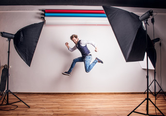 Portrait of a young hipster man in a studio, jumping. Copy space.