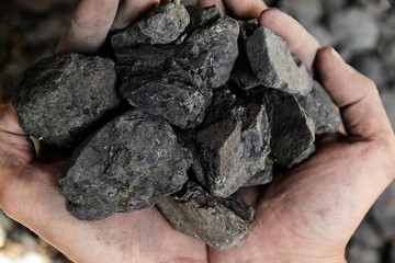 Coal miner in the man hands of coal background. Coal mining or energy source, environment protection. Industrial coals. Volcanic rock.