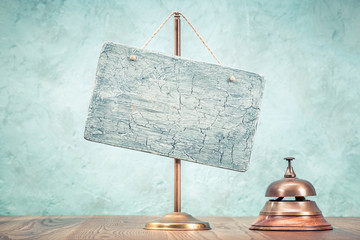 Retro hotel reception service desk bell and textured signboard blank hanging on a brass holder...