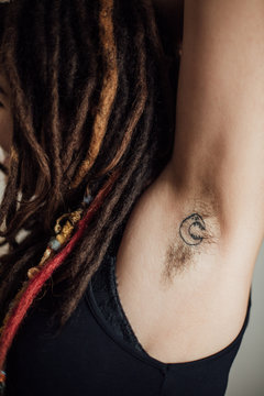 Woman with dreadlocks showing her hairy underarm with tattoo