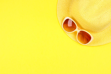 Hat, sunglasses on a pastel yellow background.