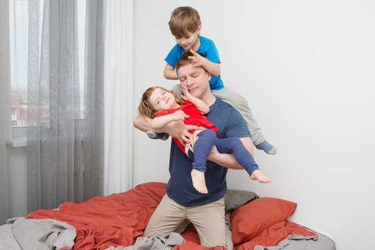 dad with two small children in his arms. The father cheerfully spends time with children.
