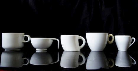 White coffee cups in a row on black background.