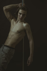 Naklejka premium Sexy, attractive guy lean on metallic pole.