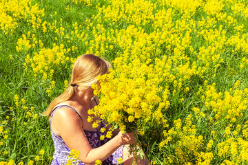 Naklejka na ściany i meble Happy blonde enjoys nature in a yellow field.