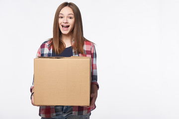 Happy excited woman holding cardboard box with expression of surprise, over white background