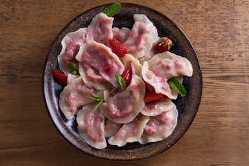 Dumplings, filled with strawberries. Pierogi, varenyky, vareniki, pyrohy - dumplings with filling. View from above, top, overhead