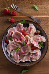 Dumplings, filled with strawberries. Pierogi, varenyky, vareniki, pyrohy - dumplings with filling. View from above, top, overhead