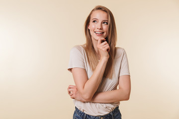 Image of affable blond woman 20s wearing casual t-shirt smiling and looking upward while standing...