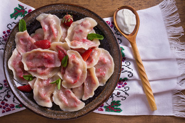 Dumplings, filled with strawberries. Pierogi, varenyky, vareniki, pyrohy - dumplings with filling. View from above, top, overhead