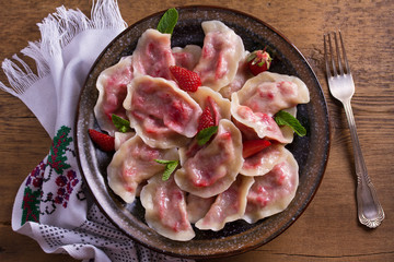 Dumplings, filled with strawberries. Pierogi, varenyky, vareniki, pyrohy - dumplings with filling. View from above, top, overhead