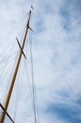 Ship mast with flag against blue sky with white clouds. Travel background.