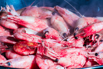 Shrimps are appetizingly fried in a skillet with sunflower oil. It is clear how from them there is a light smoke. Appetizing dish. Seafood. Food close up.