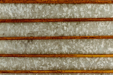 Metal background from an old rusty horizontal grid with paint remains and galvanized metal sheet.