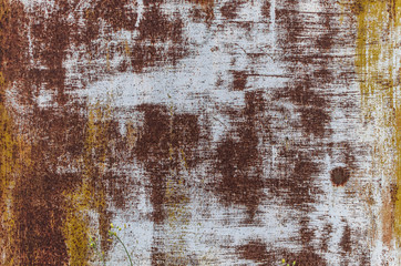A sheet of metal with a rusty texture and pieces of yellow and white paint.